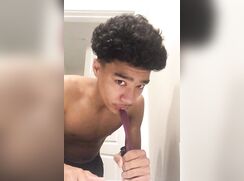 Unsmiling black boy sucking hairbrush handle