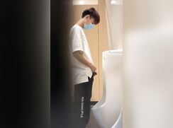 chinese boy in mask peeing at urinal