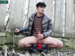 Boy wanks in the yard in jacket