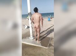 Handsome boy takes a naked shower on the beach